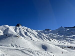 Verschneite Hänge und präparierte Spuren auf der Engstligenalp unter tiefblauem Winterhimmel