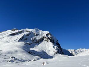 Steile verschneite Felswand auf der Engstligenalp vor klarem blauem Himmel