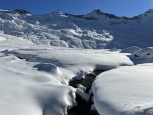Winterlicher Bachlauf auf der Engstligenalp zwischen tief verschneiten Schneehügeln