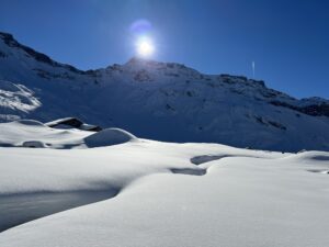 Sonnige Winterlandschaft auf der Engstligenalp mit tiefem Schnee und Bergkette im Hintergrund