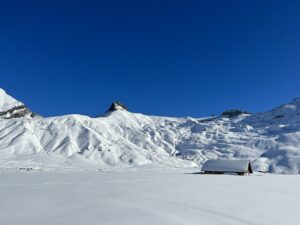 Weite Schneelandschaft auf der Engstligenalp mit Alphütte und sanften Bergflanken im Winter