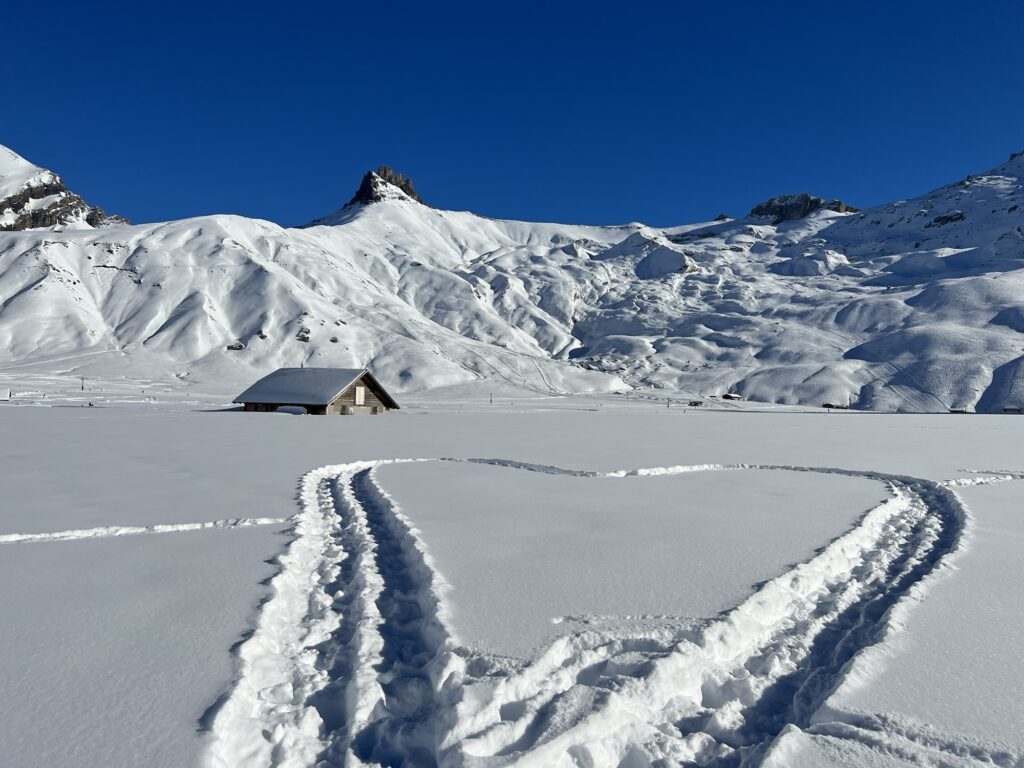 Winterliche Hochebene der Engstligenalp mit Schneespuren und Alphütte vor Bergpanorama