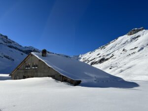 Verschneite Alphütte auf der Engstligenalp eingebettet in winterliche Berglandschaft