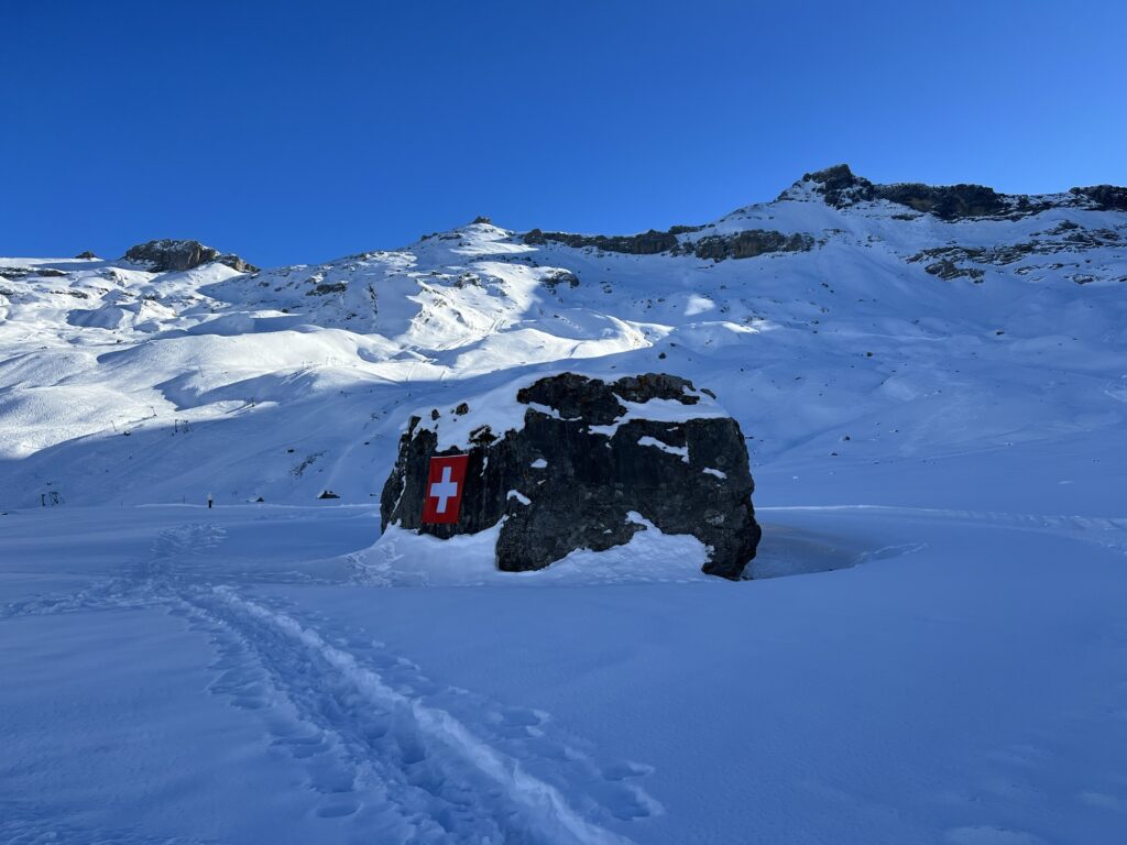 Markanter Fels mit Schweizer Fahne auf der verschneiten Engstligenalp im Winter