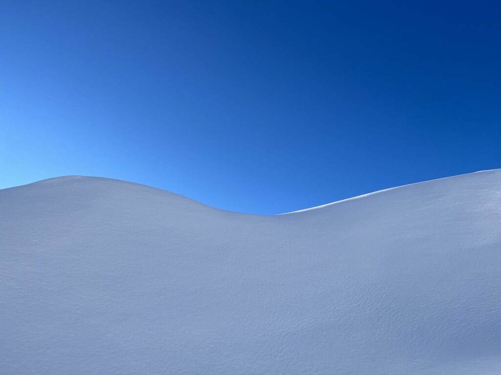 Sanfte Schneewellen auf der Engstligenalp vor tiefblauem Winterhimmel