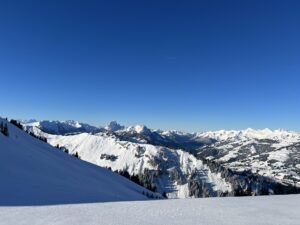 Weitblick vom Rinderberg über verschneite Hügel und Gipfel des Berner Oberlands unter tiefblauem Himmel
