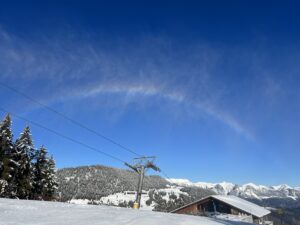 Winterwanderweg am Rinderberg mit Blick auf Skipiste, Bergbahn und verschneite Hügel