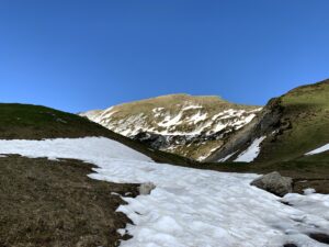 Altschneefeld auf Bergpass beim Wandern im Frühling in der Schweiz unter klarem Himmel