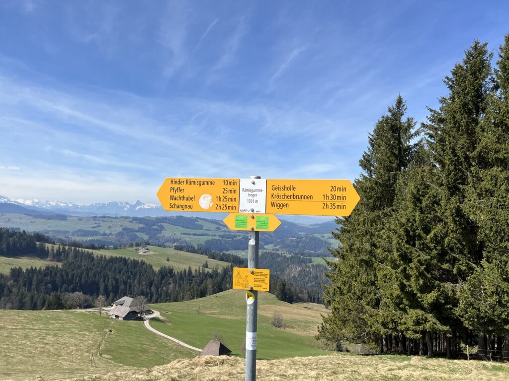 Wegweiser auf dem Rämmisgummenhoger mit Panorama auf die Berner Alpen – Aussichtspunkt der Frühlingswanderung zum Krokusfeld Rämmisgummen im Emmental.