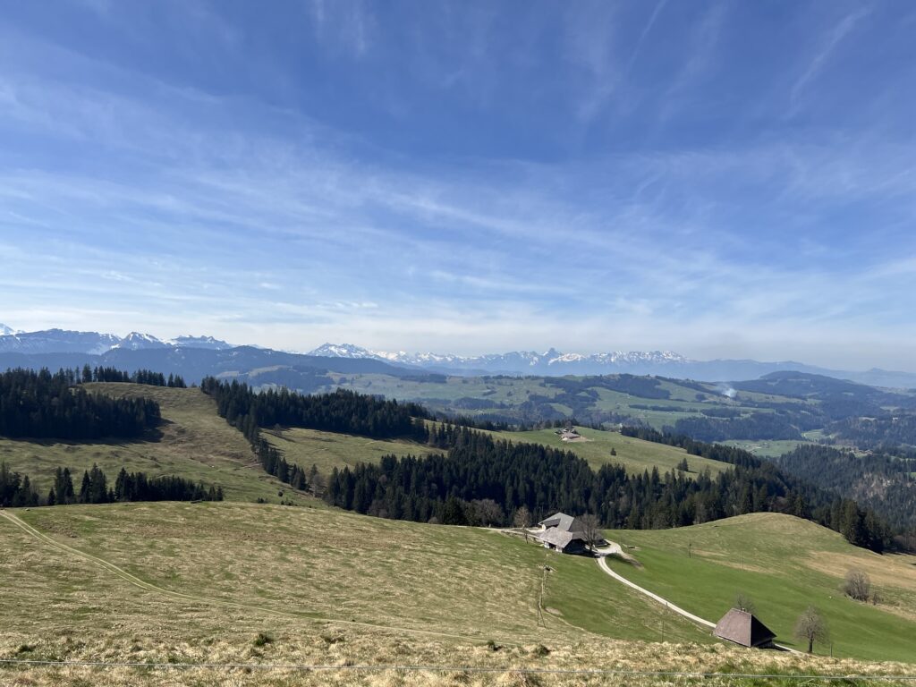 Frühlingslandschaft im Emmental mit Alpgebäude und Aussicht auf die Berner Alpen – Wandergebiet rund um Rämmisgummen.
