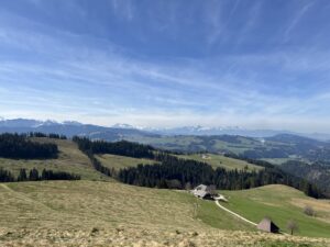Frühlingslandschaft im Emmental mit Alpgebäude und Aussicht auf die Berner Alpen – Wandergebiet rund um Rämmisgummen.