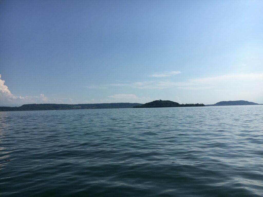 Ruhiger Bielersee mit Blick auf kleine Insel und sanfte Hügel im Hintergrund