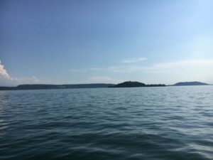 Ruhiger Bielersee mit Blick auf kleine Insel und sanfte Hügel im Hintergrund