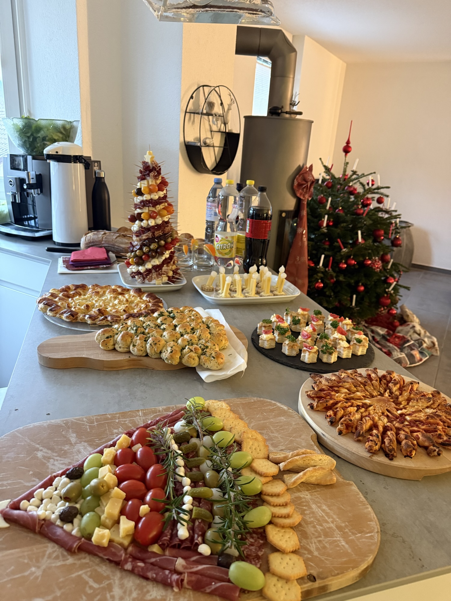 Weihnachtliches Fingerfood-Buffet mit Käseplatte, Blätterteig-Snacks und dekorierten Häppchen in moderner Küche