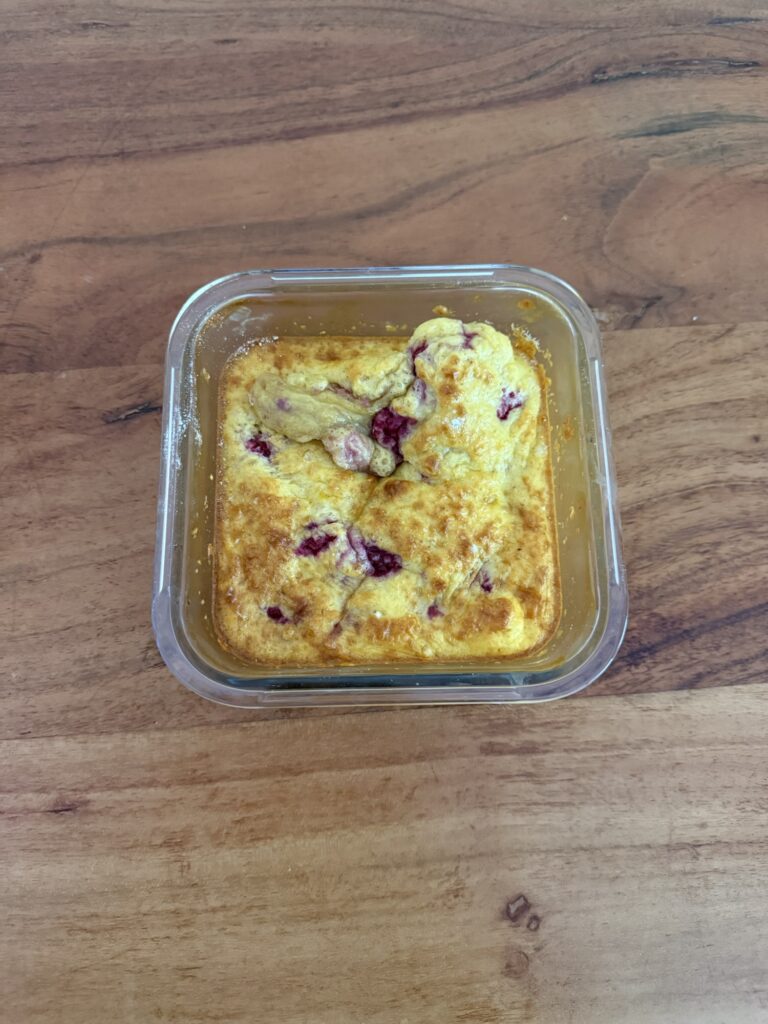 Ofen gebackener Protein Cake mit Himbeeren in Meal-Prep-Schale, gesundes eiweissreiches Frühstück mit Whey Protein und Dinkelmehl