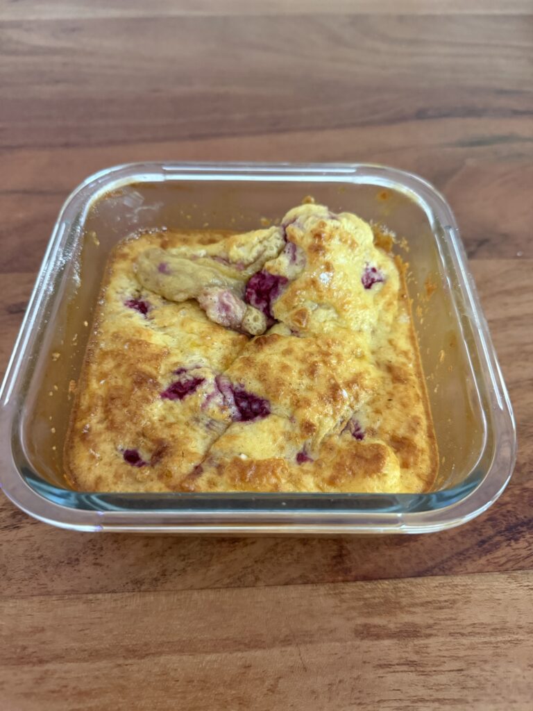 Saftiger Protein Cake mit Himbeeren und Skyr in einer Glasform, frisch aus dem Ofen gebacken, gesundes High Protein Frühstück