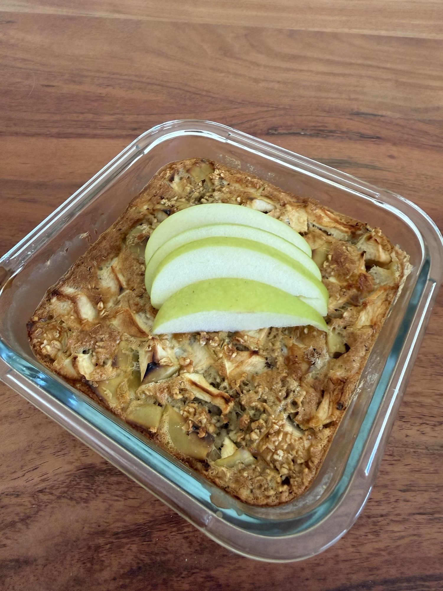 Protein Baked Oats mit Apfel in einer Glasform, frisch gebacken und mit Apfelscheiben garniert, gesundes Frühstück mit Haferflocken