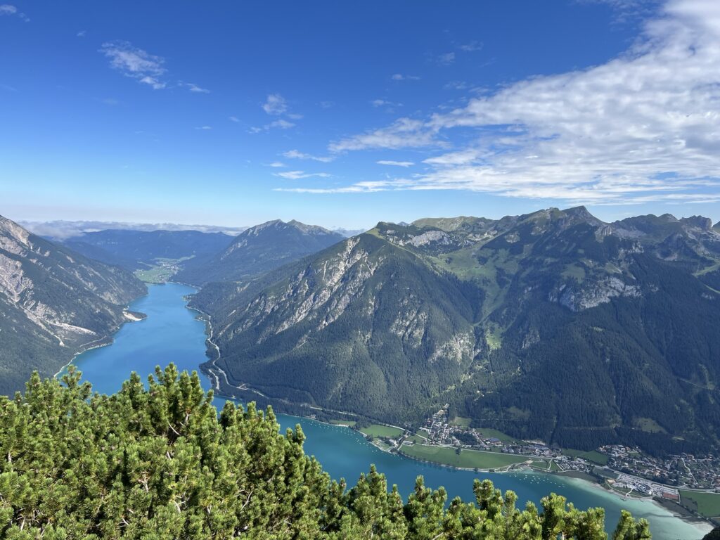 Aussicht über türkisblauen Bergsee und alpine Berglandschaft während einer Sommerwanderung in den Alpen