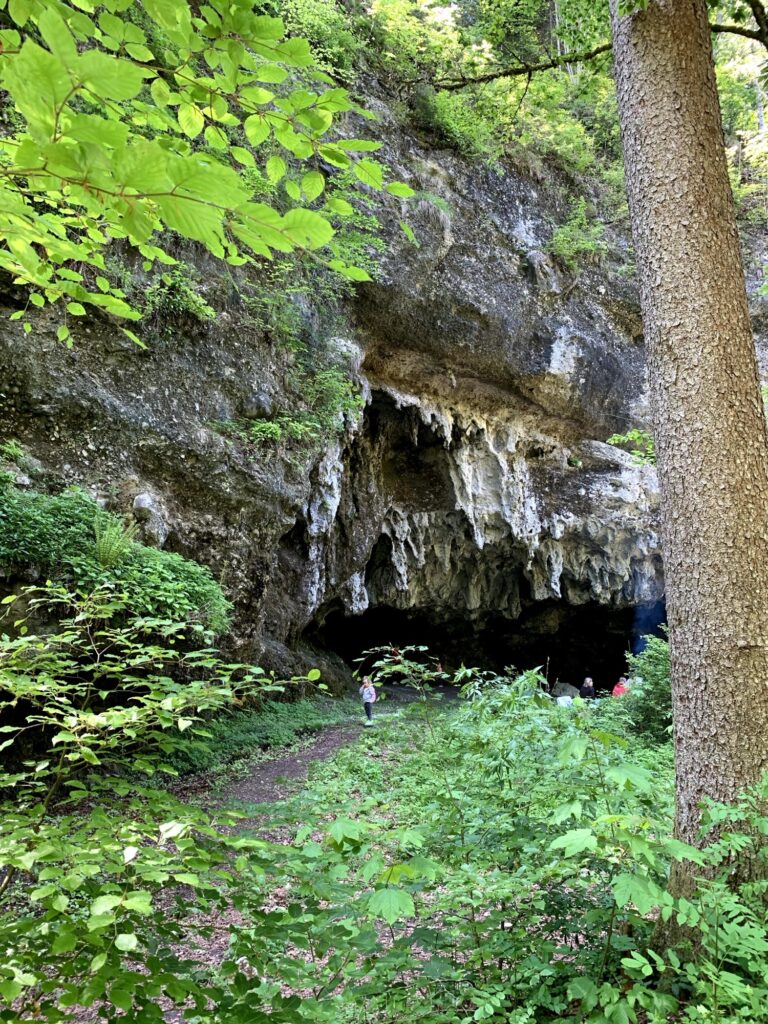 Grosse Tropfsteinhöhle im Wald bei Thun am Glütschbach mit Wanderweg und Besuchern