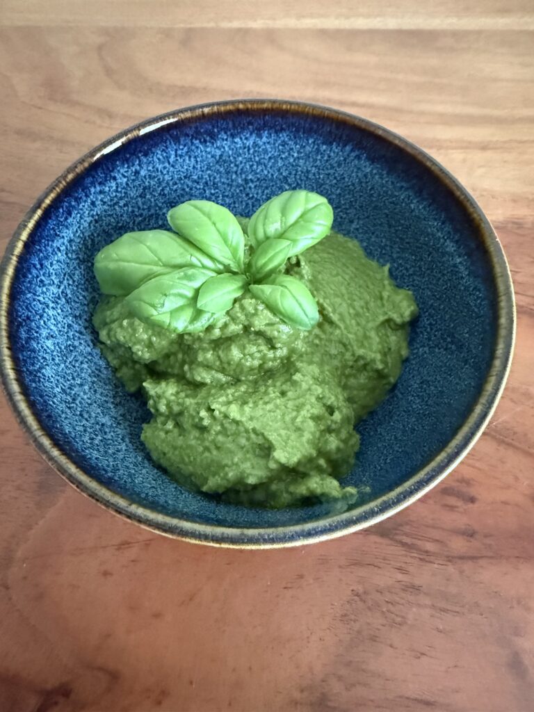 Nahaufnahme von cremigem Basilikum-Zucchini-Pesto mit frischem Basilikum