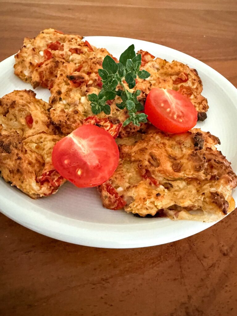 High-Protein Hüttenkäsetaler mit Cherrytomaten und frischem Oregano auf weissem Teller