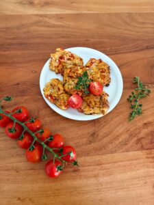 Proteinreiche Hüttenkäsetaler mit Cherrytomaten dekorativ angerichtet auf Holztisch