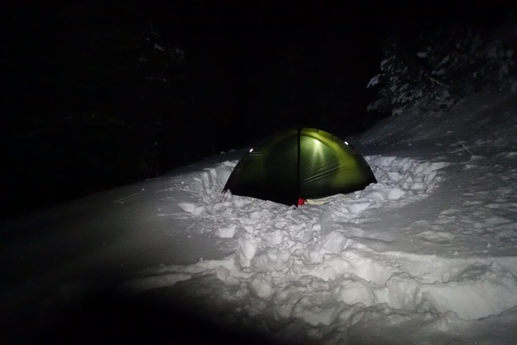 Beleuchtetes Zelt im tiefen Schnee bei einer Übernachtung alleine im Winter