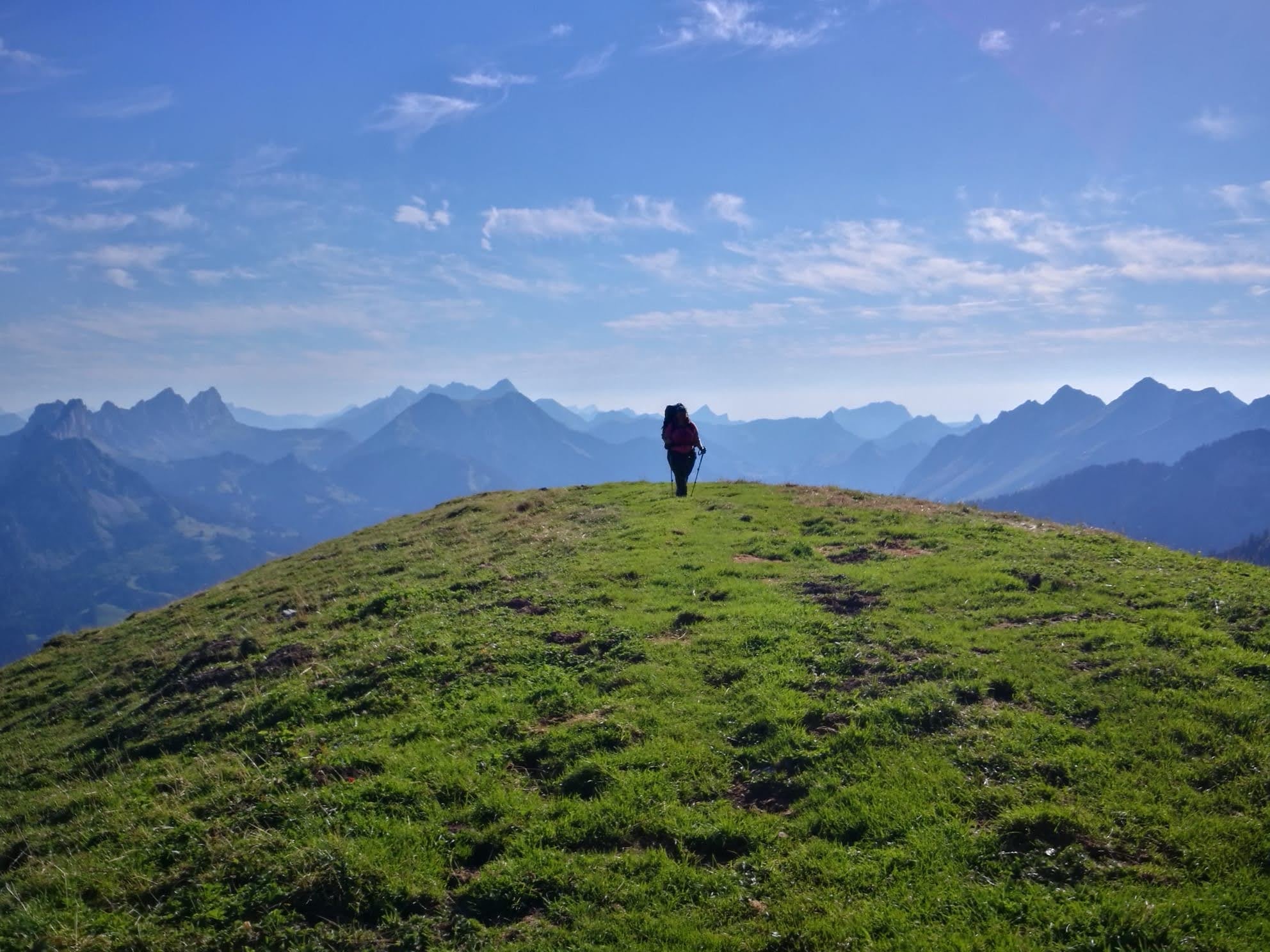 Alleine wandernde Frau mit Rucksack vor einem beeindruckenden Bergpanorama